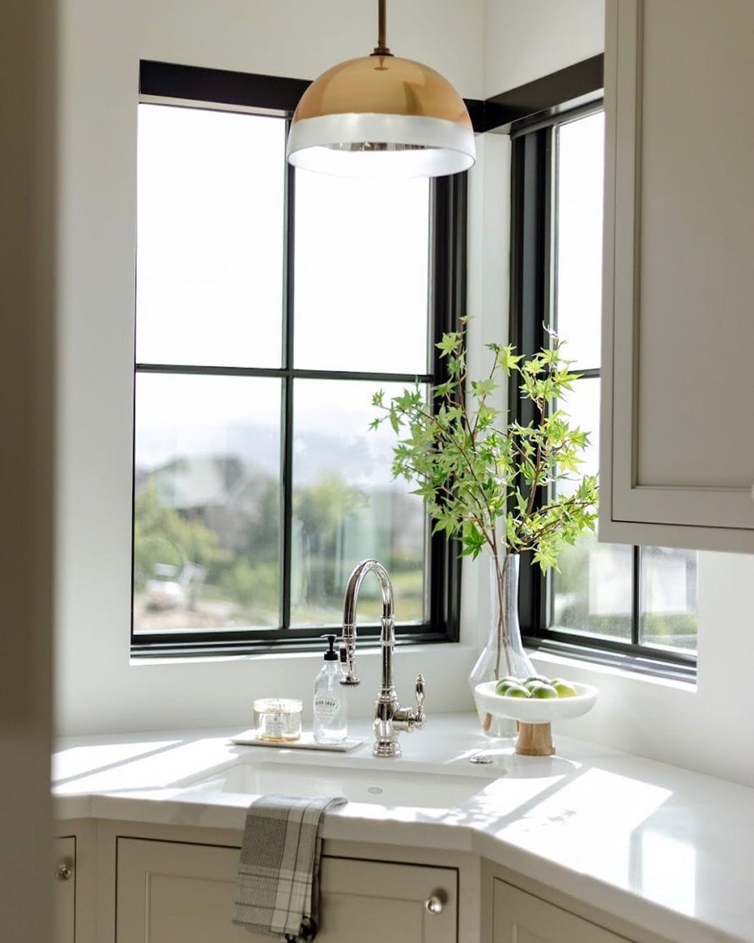 Black Picture Windows Shed Light On Classic Kitchen Corner corner kitchen sink with a fixed black window on either side and brass pendant directly above