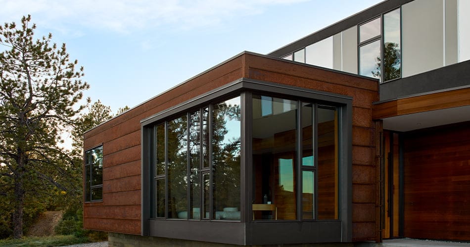 A dark, contemporary-styled home featuring floor-to-ceiling windows on the corner of the office.