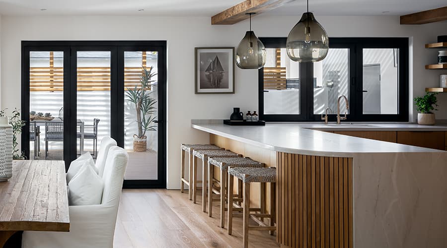 A black sliding patio door sits behind a kitchen island that includes four barstools.