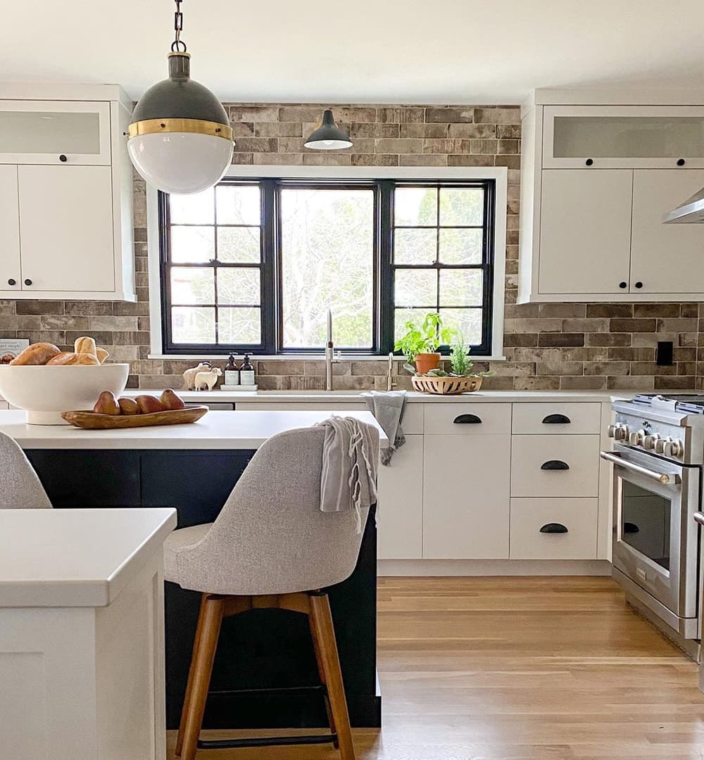 A black picture window between two single-hung windows over kitchen sink.