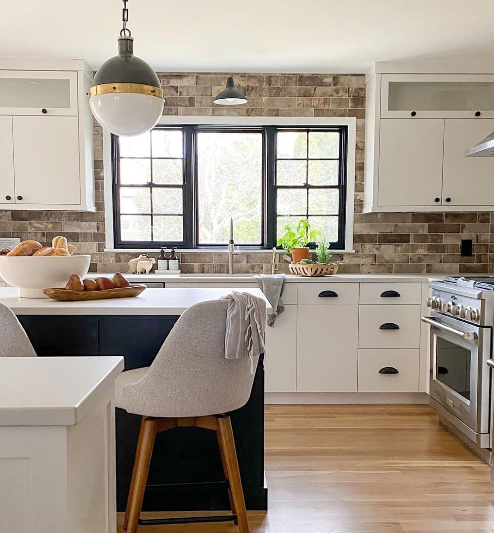 A black picture window between two single-hung windows over kitchen sink.