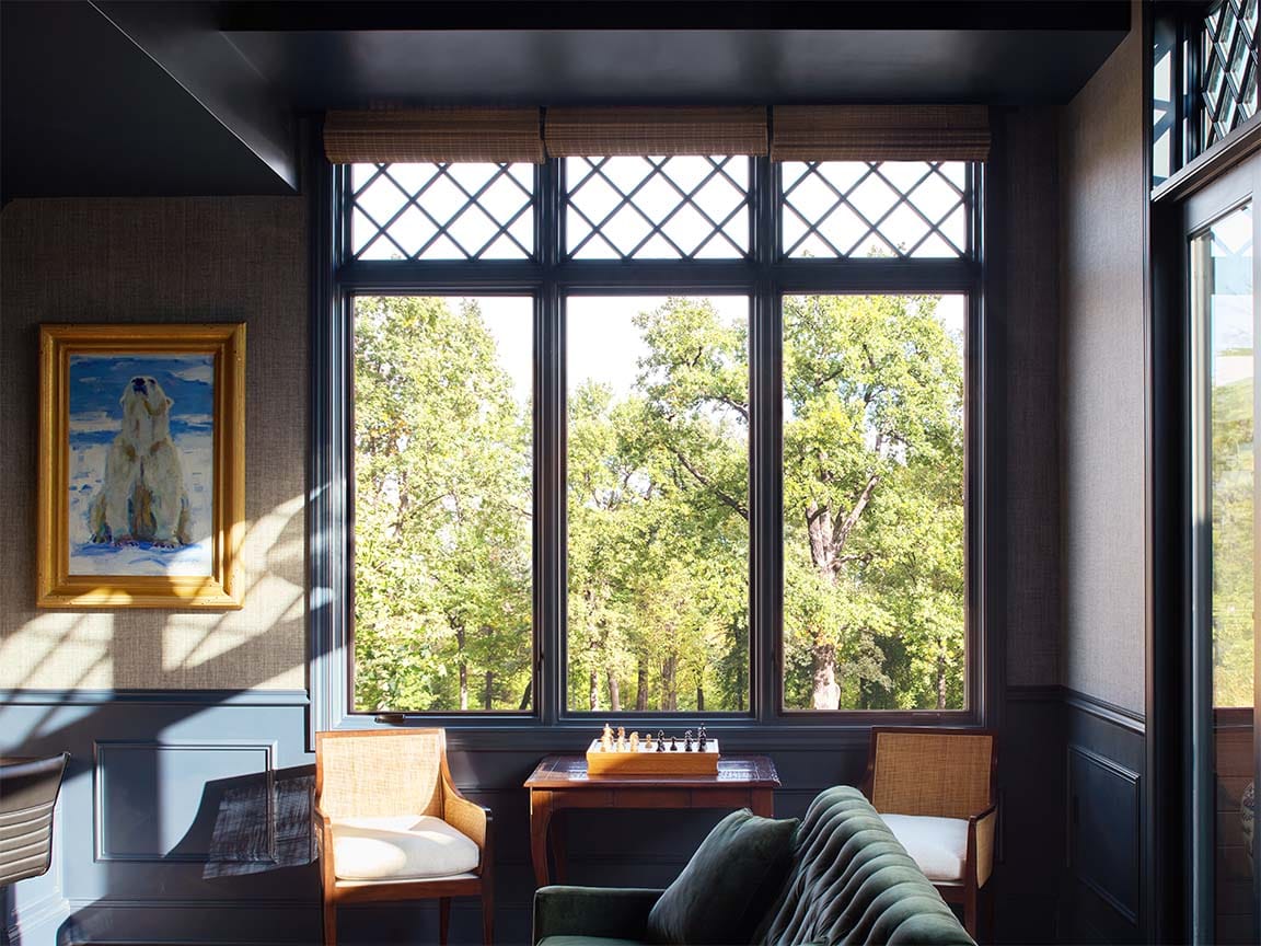 Lounge room with large blue diamond‑grid windows overlooking green trees.