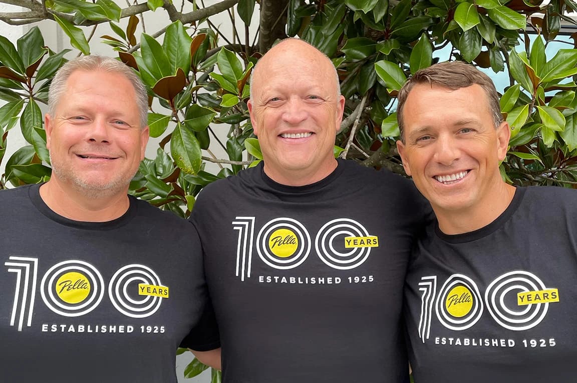 Three men in matching shirts celebrating 100 years with greenery in the background in Georgia.