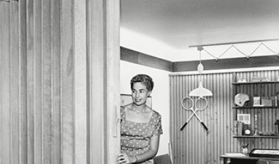 In the 1950s Pella released the wood folding door, as seen in this historical image of a woman operating the door.