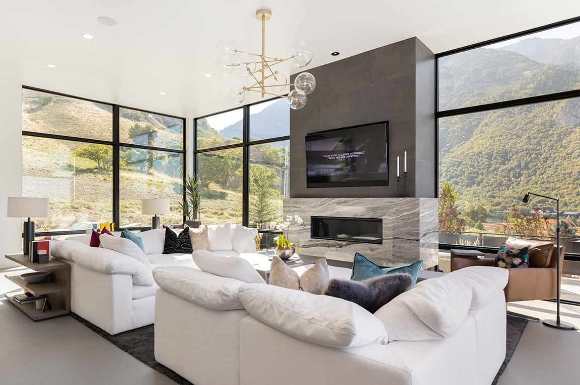 Spacious modern living room with floor-to-ceiling windows showcasing a scenic mountain view and white sofas.