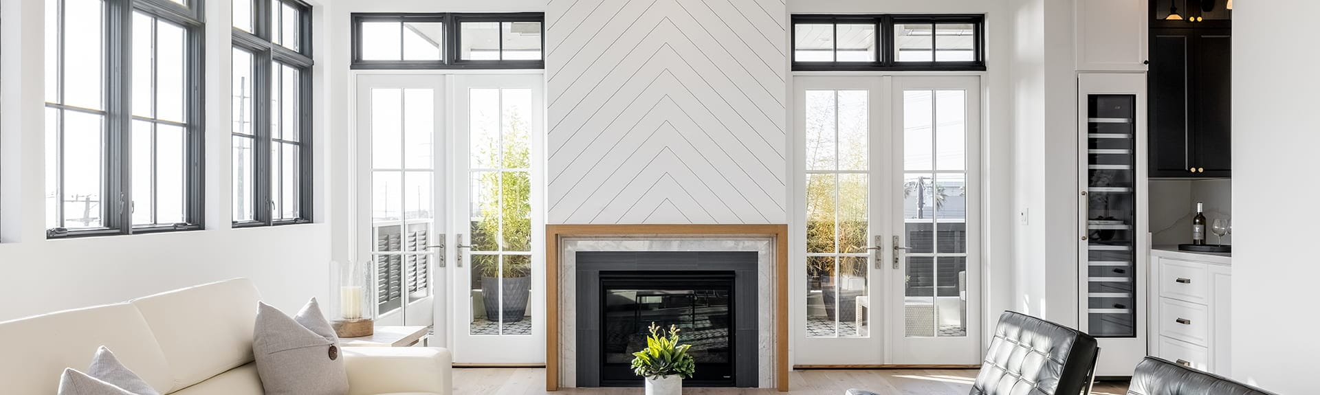 a white living room with two sets of white hinged patio doors, each with a black-trimmed transom overhead