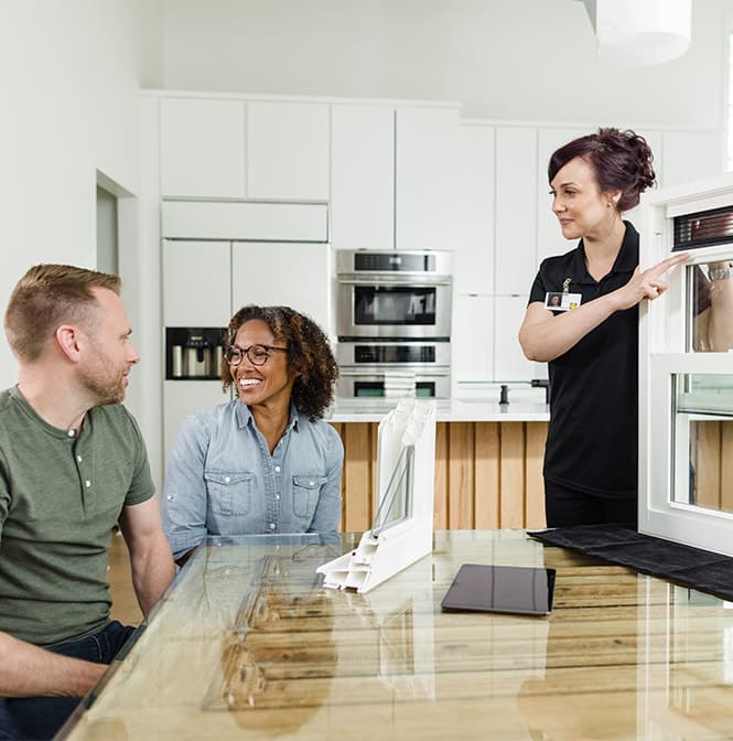A man and woman are being shown corner sections and window samples by a Pella representative