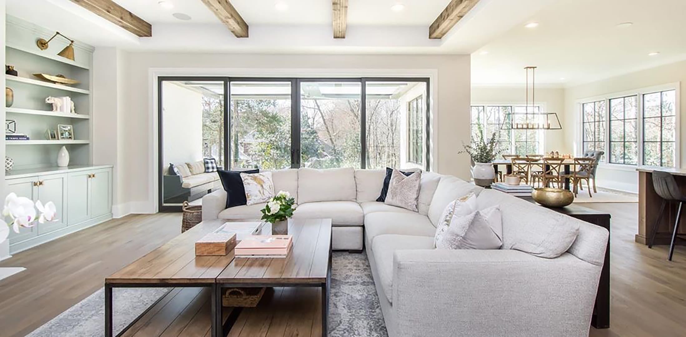 A cozy open floor plan home features a wall of black sliding patio doors connecting the living room with outdoor seating.