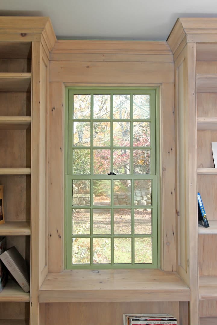 Green Window Acts As Art For Farmhouse Office green double-hung window surrounded by natural wood bookcase on either side