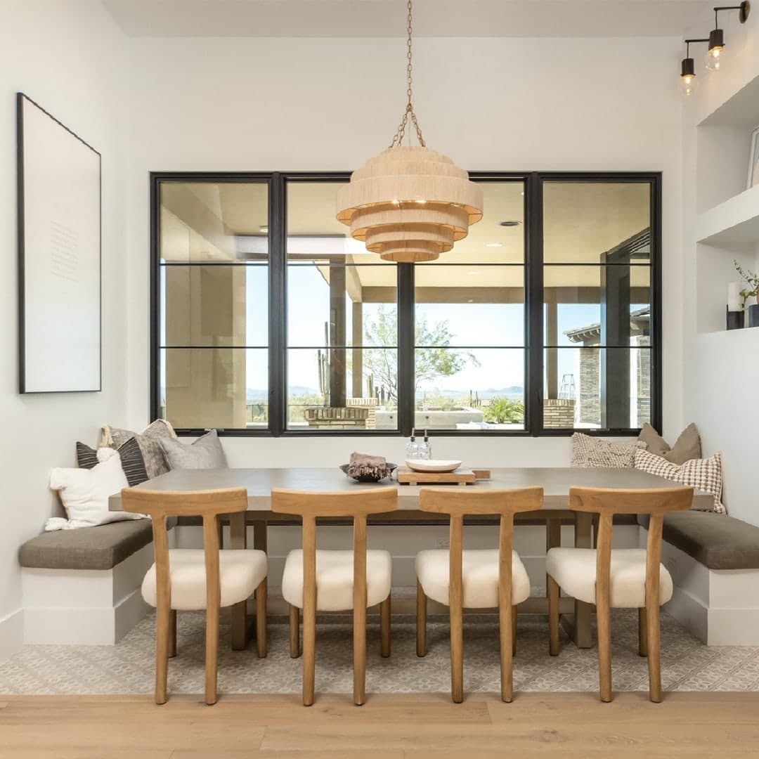 A modern dining room features black windows with horizontal grilles behind the table.