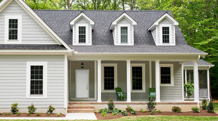 a gray cape cod-style home with three dormer windows