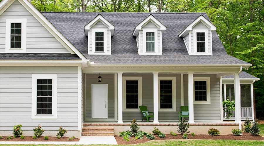 a gray cape cod-style home with three dormer windows