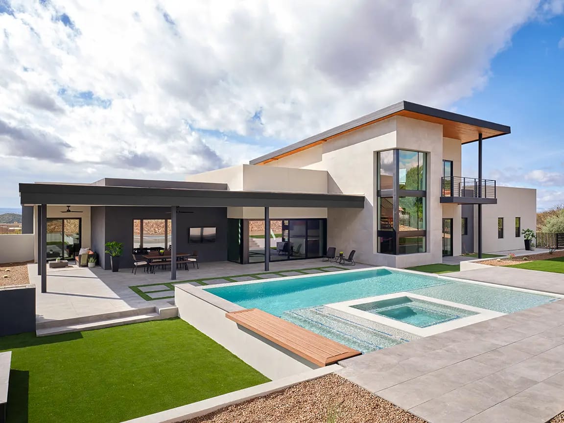 Contemporary two-story luxury home with rectangular swimming pool and built-in spa, covered patio dining area, and desert landscaping