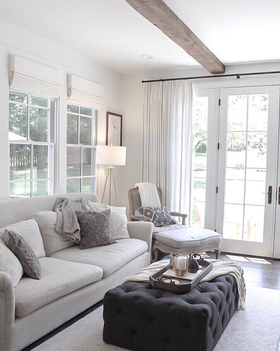 Classic French Doors Shed Light on Cozy White Living Room white on white living room couch, chair, and gray ottoman next to set of white french doors