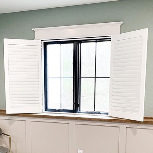 white shutters on two casement windows in a seafoam green room