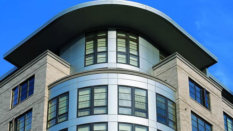 close shot of a rounded corner office building with steel-like siding