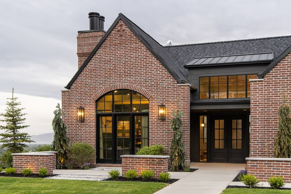 The front of a red brick house features black doors and windows, lending traditional style.
