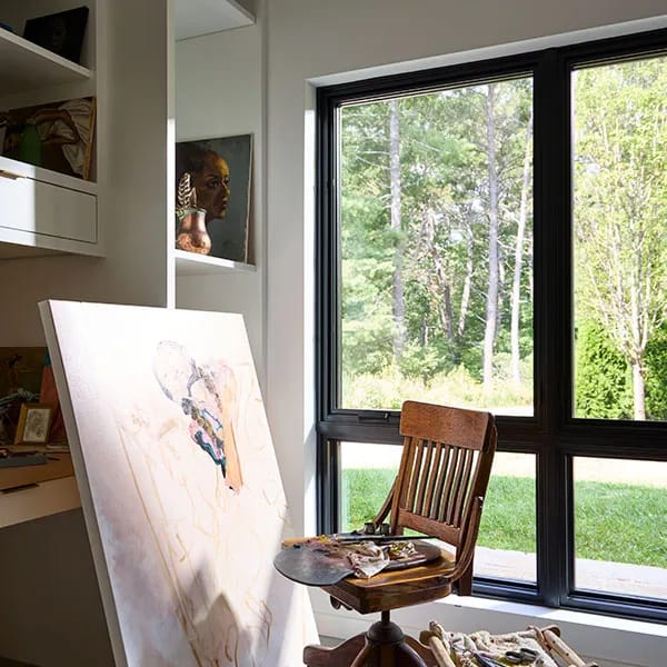 An artist's studio features a canvas, wooden chair, and large window, showing creative combinations of art and nature.