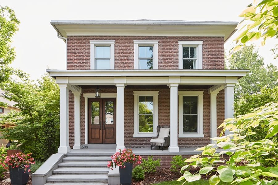 Double Doors & Double-Hung Windows Uphold Traditional Design Two story red brick house with white double-hung windows and a wood double door with glass