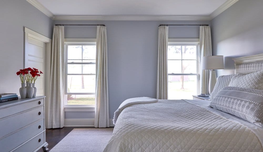 Energy Efficient Vinyl Windows Create Comfortable Bedroom Neutral colored bedroom with bed in front of two double-hung vinyl windows with white & gray striped curtains