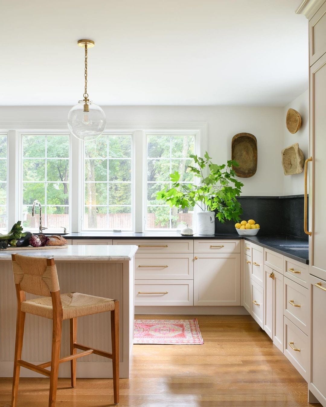White windows with grilles act as kitchen window backsplash above black counters.