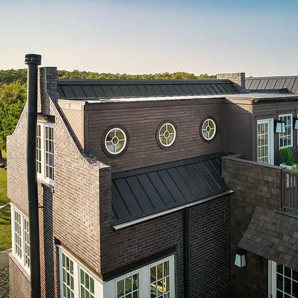 Three round windows with decorative grilles on a brown brick house exterior.