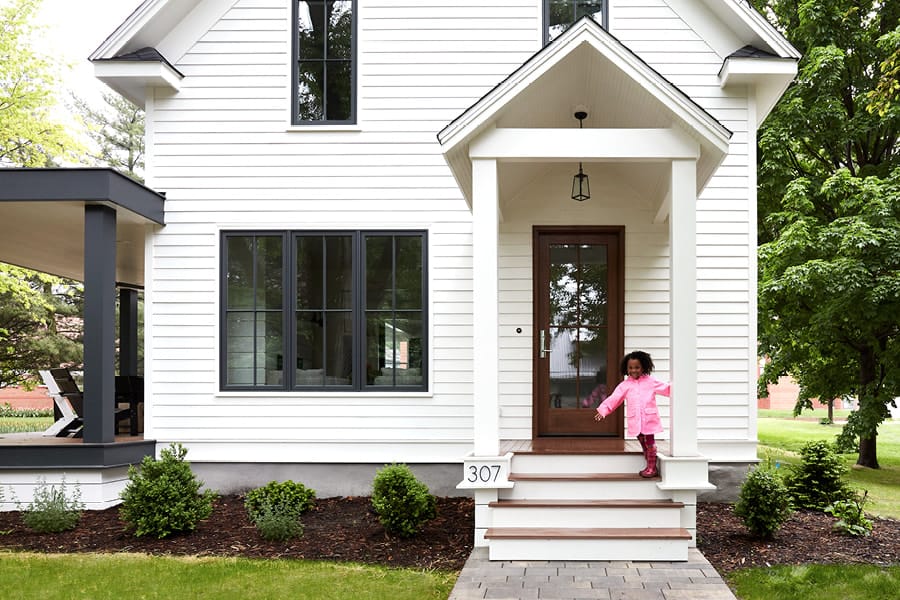 White Farmhouse Home with Wood Entry Door and Deck