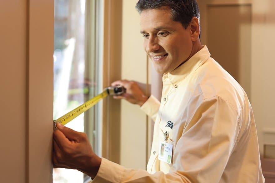 man measuring a window with tape measure