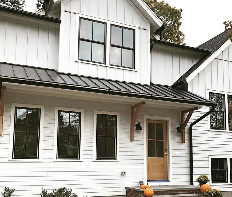 Black Windows Match Exterior Accents On Modern Farmhouse White modern farmhouse with black double-hung windows and wood stained front door