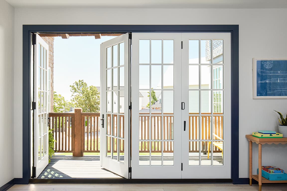 White French doors open to a patio with a wooden railing, showcasing sliding door ideas.