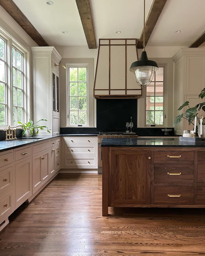 A white kitchen with a wood island features casement windows behind the sink and on both sides of the stove.