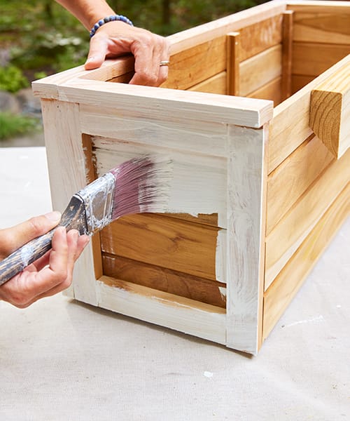 Applying a primer base coat of paint to a wood window box.