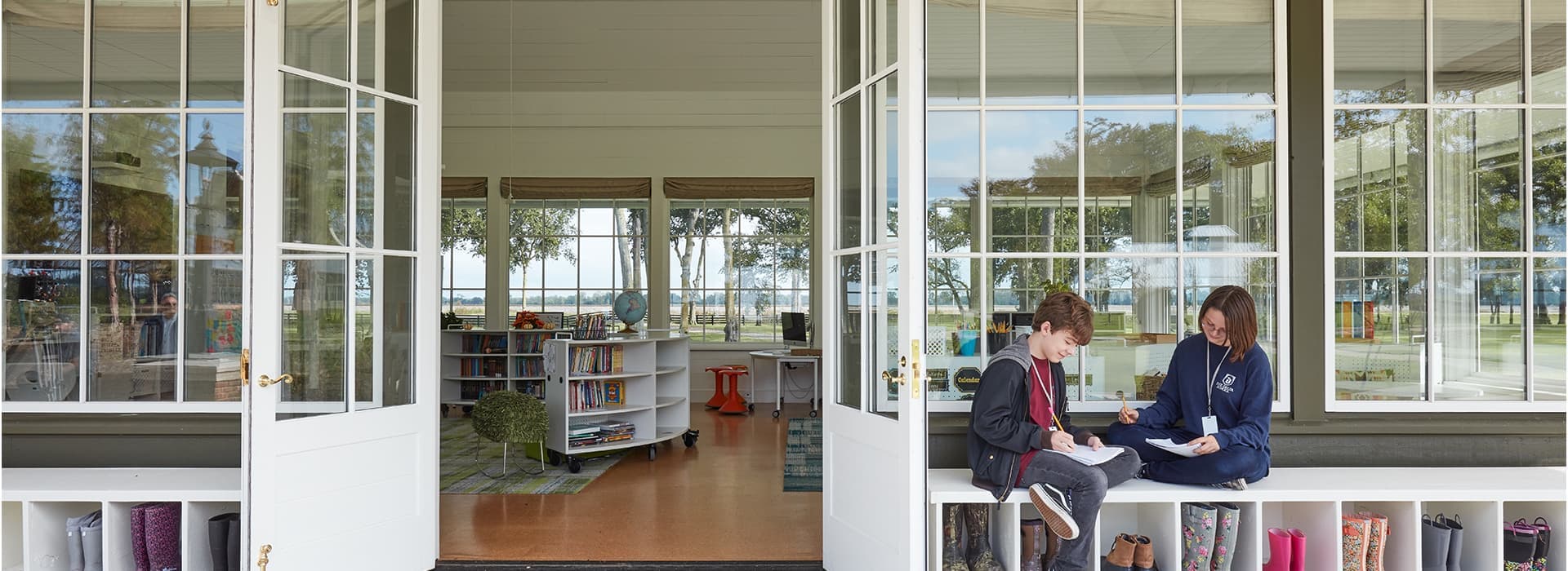 two children sitting outside a school library with pella windows and doors