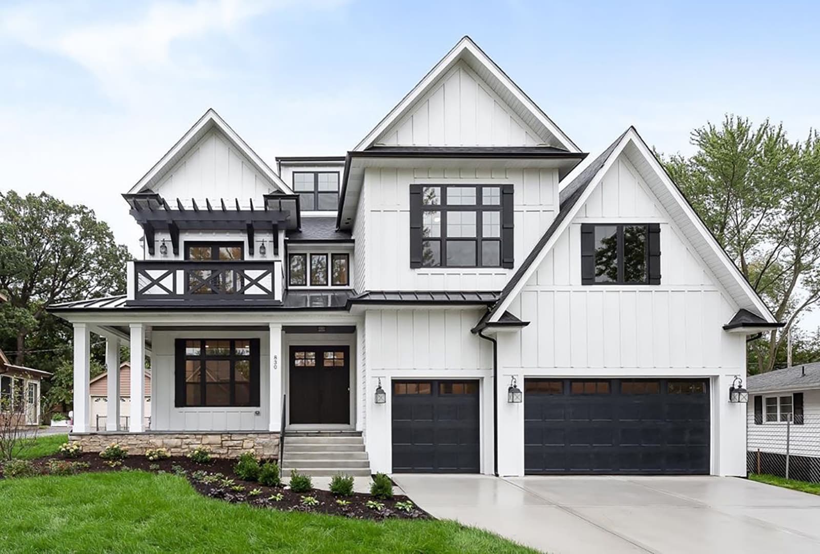 Exterior view of white farmhouse-style home with several black windows.