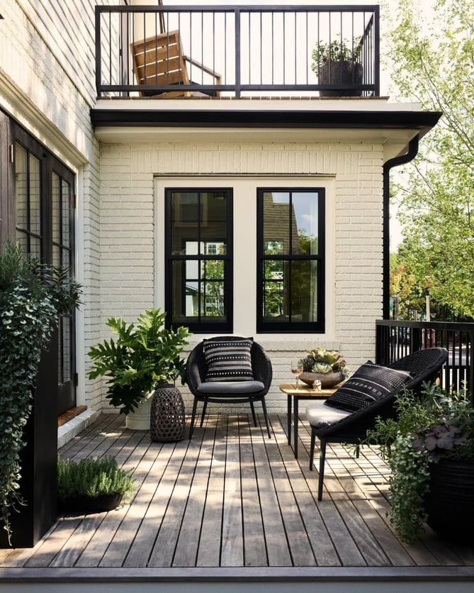 The exterior of a white home showcases black double-hung windows on a modern-style deck.