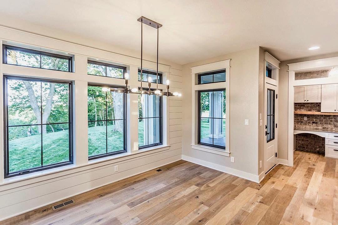 Black Windows With White Trim Creates Modern Farmhouse Look black window frames with white trim in a room with shiplap walls and wood flooring