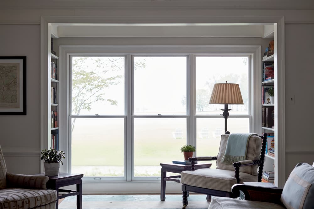 Floor-To-Ceiling Double-Hung Windows Add Timeless Style Three floor-to-ceiling double-hung windows flanked by bookcases on either side in living room