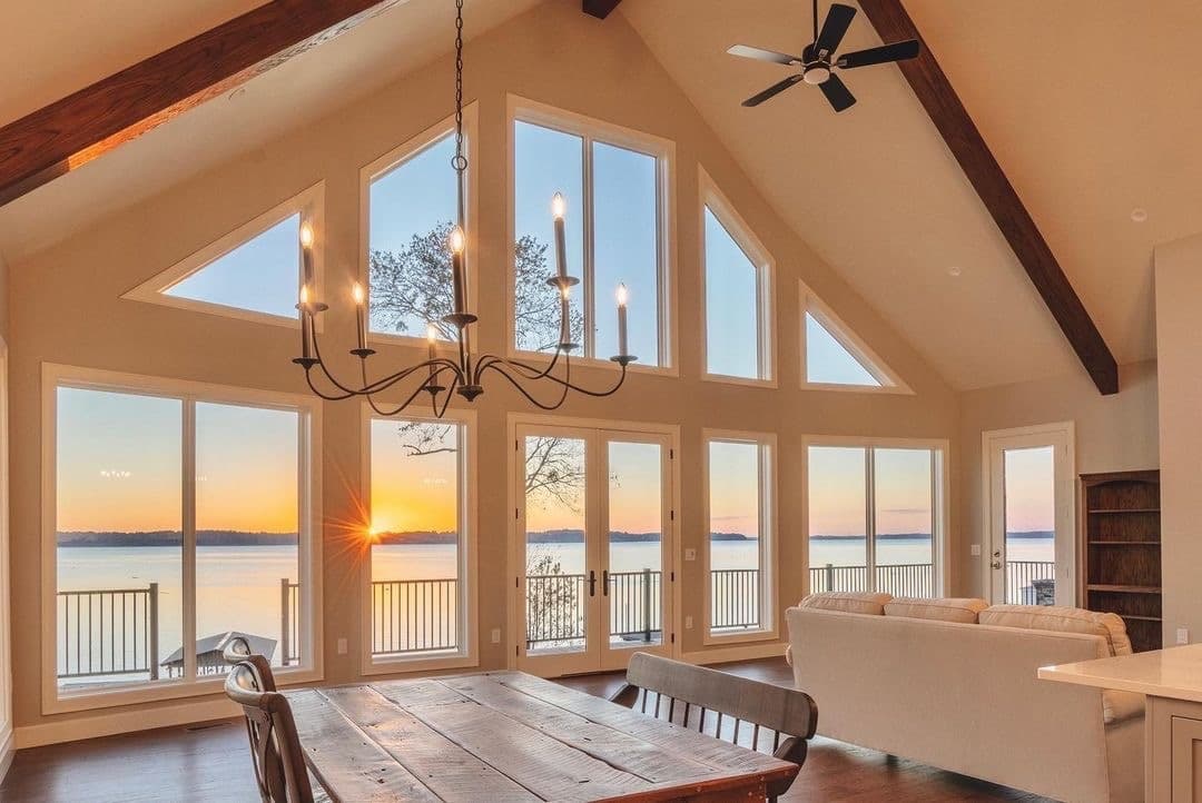 A living room features a large window wall with triangle windows that overlook a lake.