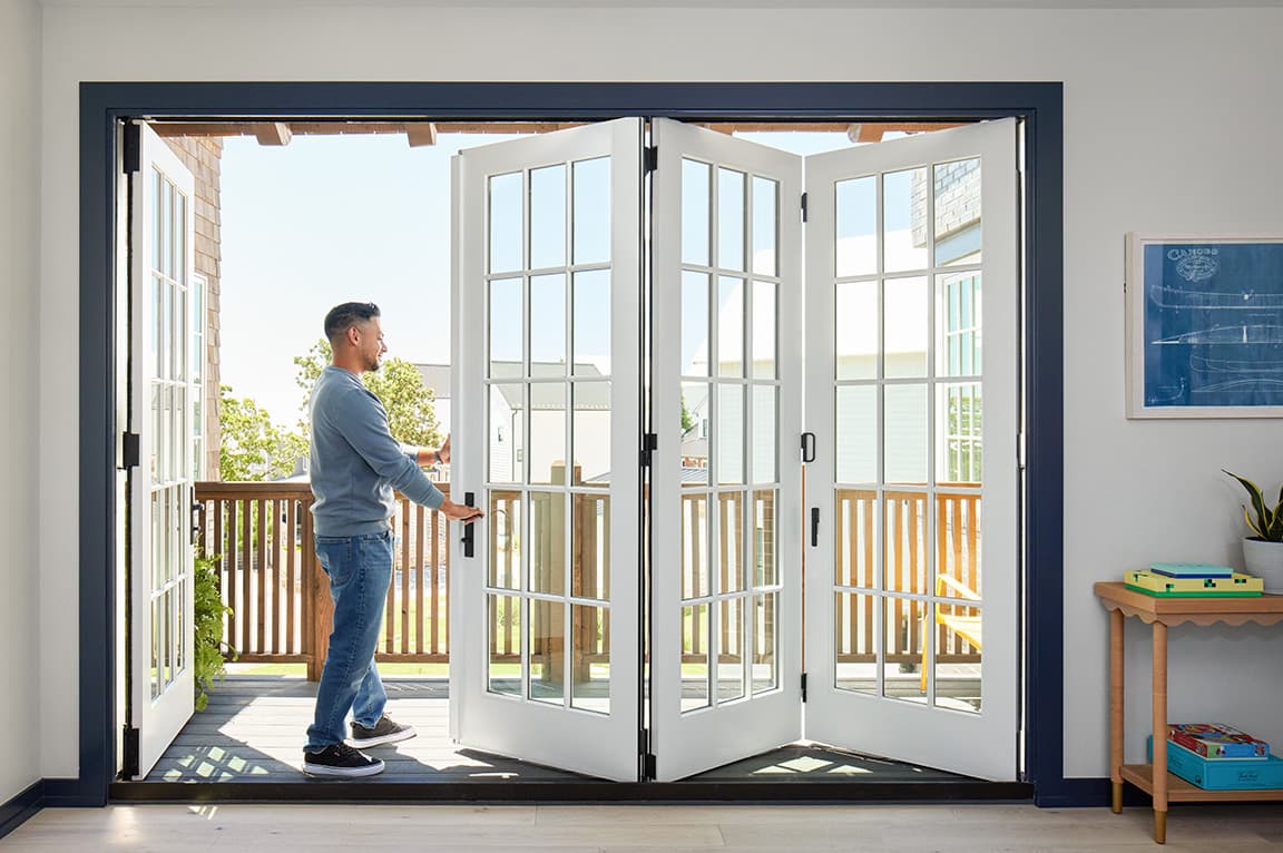 A man opening white French doors to a patio, showcasing stylish sliding door ideas.